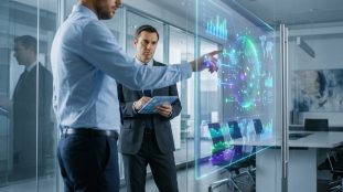 Deux professionnels en costume analysent des données numériques interactives projetées sur une paroi en verre.